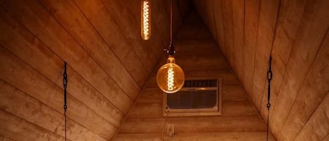 Une chambre confortable située dans les combles, avec un lit, des luminaires suspendus et une fenêtre.