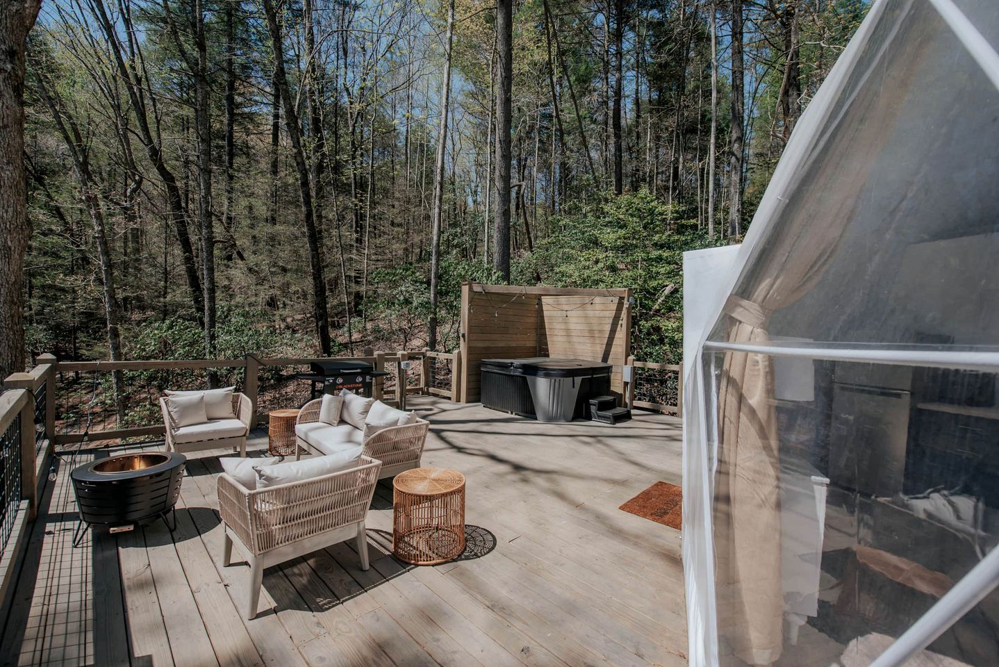 A wooden deck with wicker furniture, a grill, and a hot tub.