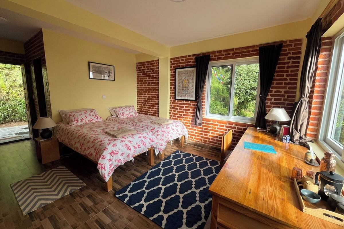 Un dormitorio con cama, escritorio, ventana y pared de ladrillo.