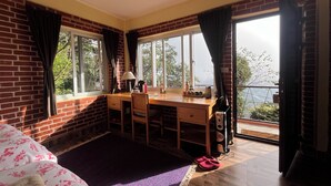 Una habitación con escritorio de madera, una silla, un radiador y vistas al exterior.