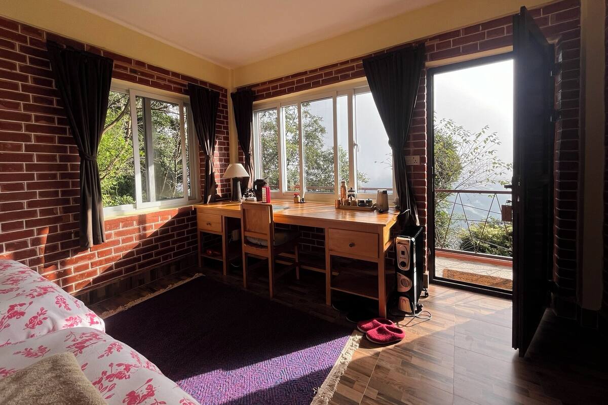 Una habitación con escritorio de madera, una silla, un radiador y vistas al exterior.