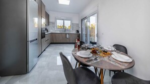 Een moderne keuken met een eethoek, met een roestvrijstalen koelkast, een inbouwoven en een eettafel gedekt voor vier personen.
