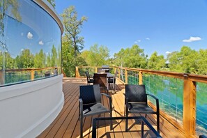 A deck with outdoor seating, a grill, and a view of a lake. - Outstanding Luxurious Dome with Mini Golf, Outdoor Bath, Sauna and Lake Views in Elgin, Texas (Elgin)