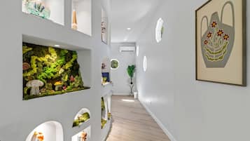 A hallway with a glass aquarium, framed artwork, and a potted plant.