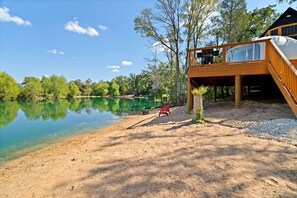 A lakeside cabin with a deck, a chair, and a fishing rod. - Outstanding Luxurious Dome with Mini Golf, Outdoor Bath, Sauna and Lake Views in Elgin, Texas (Elgin)