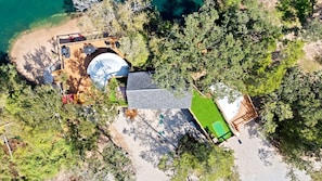 An aerial view of a property with a swimming pool, outdoor seating, and a tennis court.