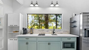 Una cocina moderna con un ventanal grande, electrodomésticos integrados y una distribución limpia y ordenada.