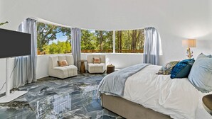 A bedroom with a large bed, two armchairs, a TV, and a window with curtains. - Outstanding Luxurious Dome with Mini Golf, Outdoor Bath, Sauna and Lake Views in Elgin, Texas (Elgin)