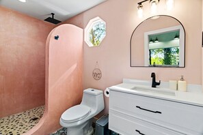 Une salle de bain comprenant des toilettes, un lavabo avec un miroir et un espace douche.