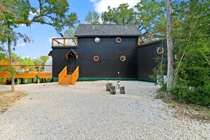 A building with a black exterior, wooden staircase, and a gravel ground.