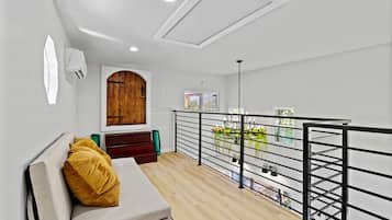 Een modern interieur met een houten deur, een bank met een kussen, een trap en een balkon met een leuning.