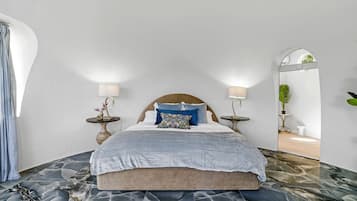 Ein Schlafzimmer mit einem Bett, zwei Nachttischen, einem Spiegel und einer Zimmerpflanze.