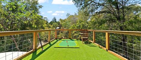 Un parcours de mini-golf doté d’une terrasse en bois et d’une surface de jeu artificielle verte.