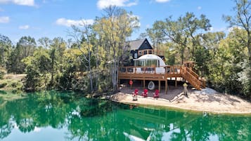 A lakeside cabin with a large deck, a covered outdoor area, and a swimming pool.