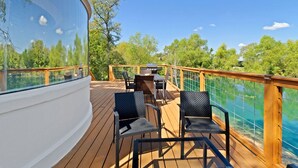 A deck with outdoor seating, a grill, and a view of a lake. - Outstanding Luxurious Dome with Mini Golf, Outdoor Bath, Sauna and Lake Views in Elgin, Texas (Elgin)