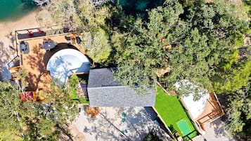 An aerial view of a property with a swimming pool, outdoor seating, and a green lawn.