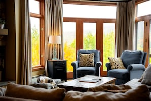 A cozy living room with a fireplace, two armchairs, a coffee table, and a dog bed.
