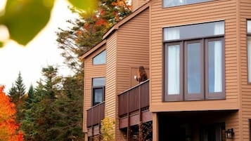 A two-story building with a balcony, large windows, and a grassy yard.