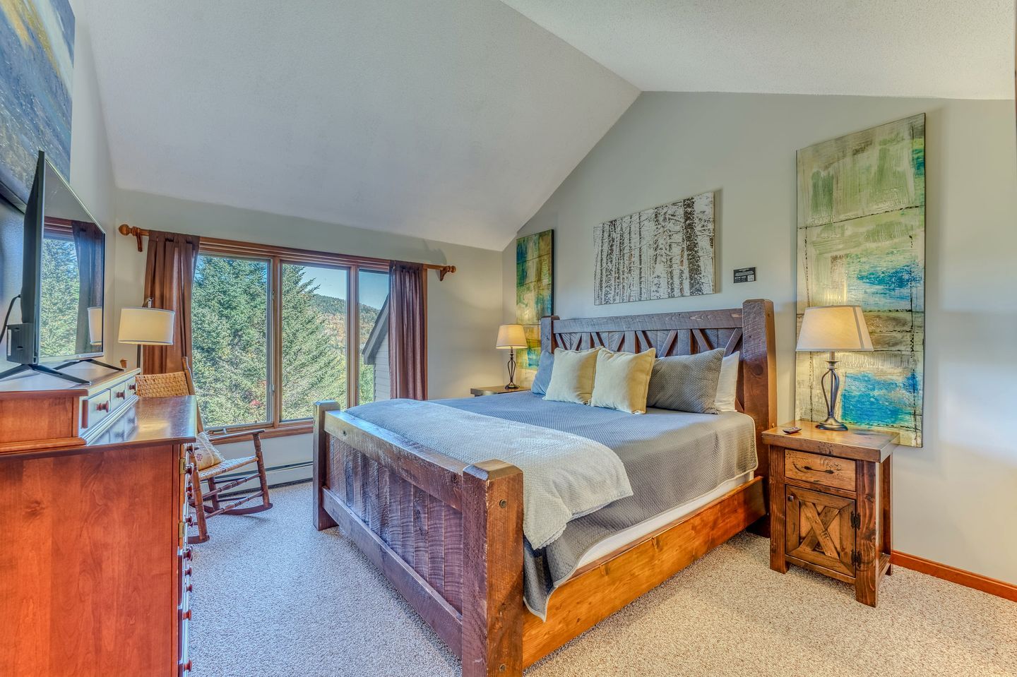 A bedroom with a large bed, bedside tables, a desk, and a window with curtains.