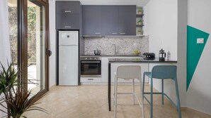 A compact kitchen with a refrigerator, oven, sink, and bar stools. - Rodini Anassa | Apollo, Apartment (Rodos)