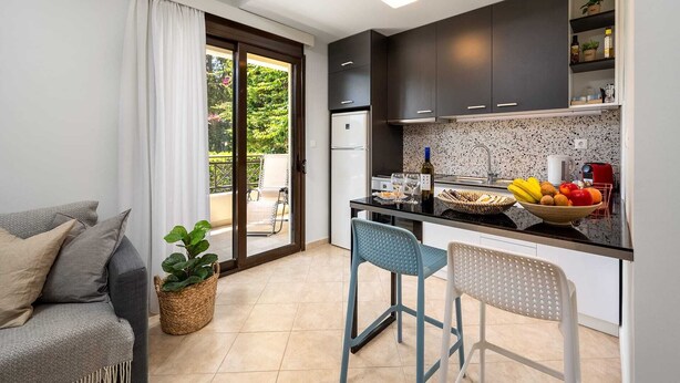 A compact kitchen with a dining area, a refrigerator, a sink, and a small bar area. - Rodini Anassa | Apollo, Apartment (Rodos)