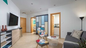 A modern living room with a sofa, a TV, a coffee table, and a chair. - Rodini Anassa | Apollo, Apartment (Rodos)