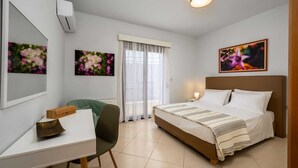 Une chambre d’hôtel avec un lit, un bureau, une chaise, un radiateur et deux tableaux accrochés aux murs.
