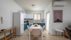 Une cuisine compacte comprenant un coin repas, une petite table, une chaise et un climatiseur mural.