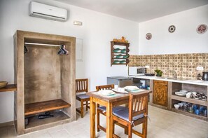 A compact kitchen with a dining area, a built-in oven, and a microwave. - Summer Paradise Stegna (RODOS)