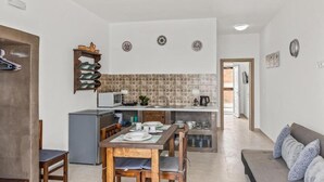 A compact kitchen with a dining area, a built-in oven, and a small refrigerator. - Summer Paradise Stegna (RODOS)