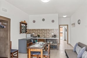 A compact kitchen with a dining area, a built-in oven, and a small refrigerator. - Summer Paradise Stegna (RODOS)