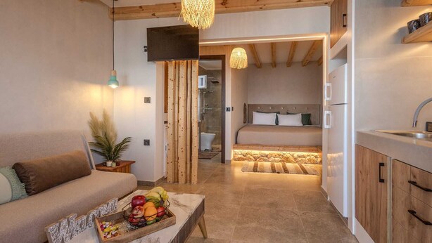 Um quarto aconchegante com sofá, cesta de frutas, cama e cozinha.