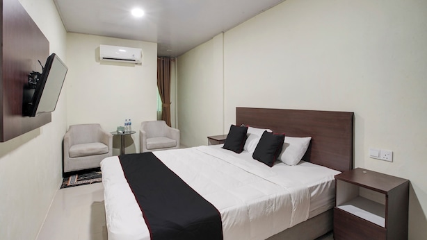 Habitació d'hotel amb un llit gran, dos seients, una taula petita i una tauleta de nit.
