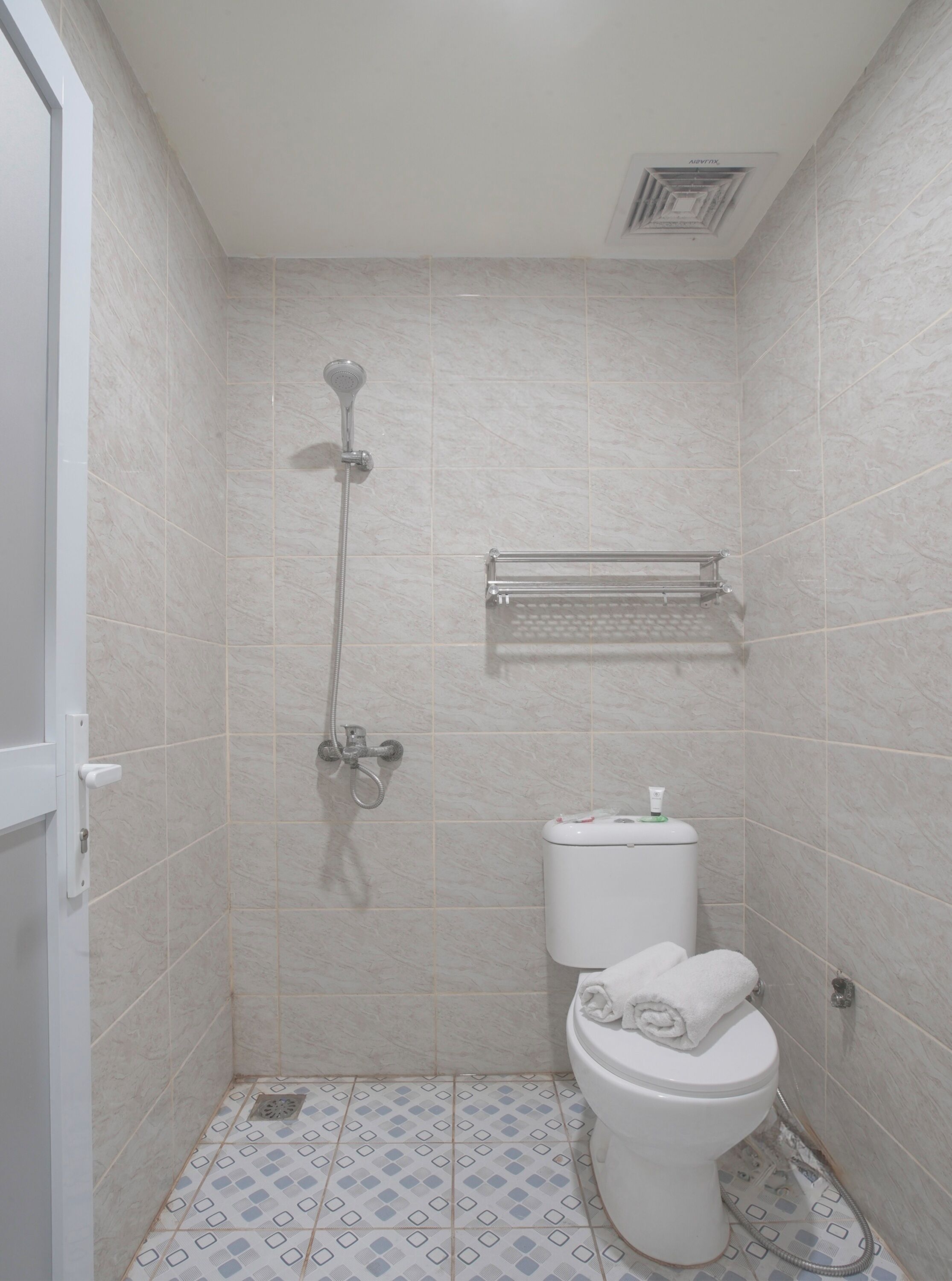 A small bathroom with a toilet, a shower, and a towel rack.