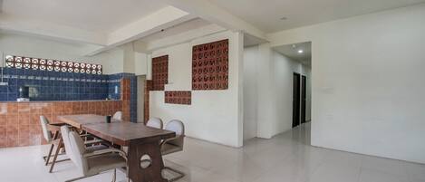 A spacious room with a wooden dining table and chairs, a tiled backsplash, and decorative panels on the walls.