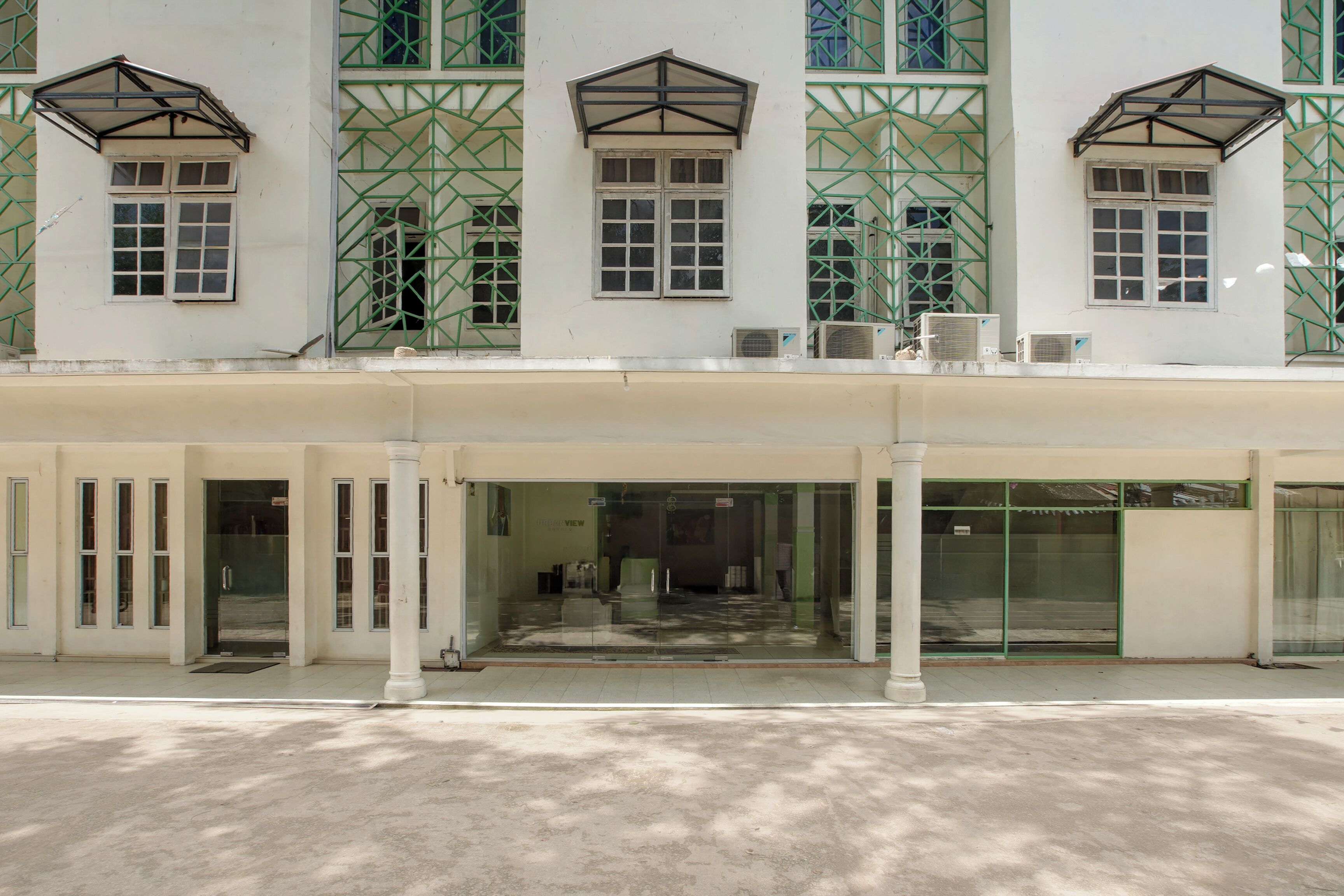 A building with a covered entrance, multiple windows, and air conditioning units.