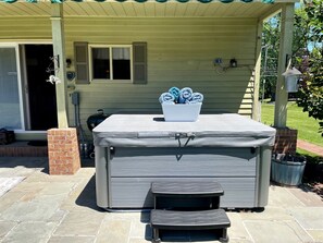 A covered outdoor hot tub with a bench, a brick planter, and a house in the background. - Incredible Cottage with Hot-tub in Penn Yan, New York (Penn Yan)