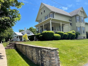 A two-story house with a porch, stone wall, and well-maintained lawn. - Incredible Cottage with Hot-tub in Penn Yan, New York (Penn Yan)