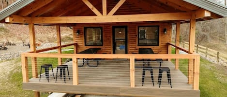A wooden cabin with a porch, two windows, and a door.