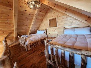A wooden cabin with two beds, a small table, and a ceiling fan. - Group Friendly Cabin with Spa on the Deck near Tappan Lake in Ohio (Deersville)