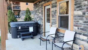 Un edificio de piedra con un patio cubierto, asientos al aire libre y un jacuzzi.