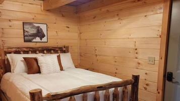 Un dormitorio de cabaña de madera con cama, cabecera de madera y lámpara en el techo.