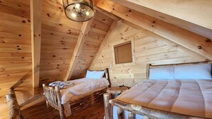 Una cabaña de madera con dos camas, una mesita y un ventilador de techo.