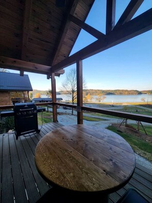 A wooden deck with a table and grill, overlooking a lake and hills. - Group Friendly Cabin with Spa on the Deck near Tappan Lake in Ohio (Deersville)