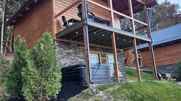 Una cabaña de troncos de dos pisos, con cimientos de piedra, un porche cubierto y un garaje.