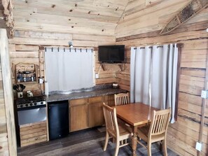 A compact kitchen with a stove, sink, and a dining area with chairs and a table.