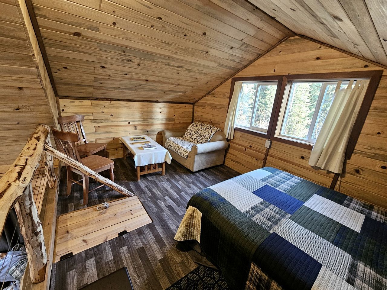 A cabin interior with a bed, a sofa, a table, and a chair.