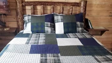 A bed with a quilt, wooden headboard, and a wall with a wooden log.