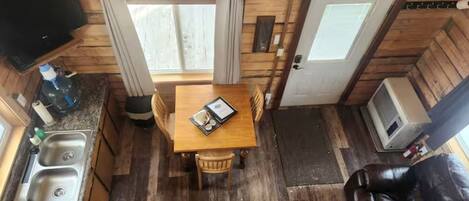 Una cocina compacta con una mesa de comedor, dos sillas, un lavabo y un televisor.