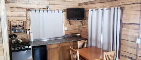 Una cocina compacta con estufa, lavamanos y comedor con sillas y mesa.